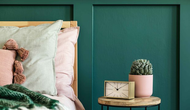 Stylish-bedroom-interior-with-design-coffee-table-plant-gold-clock-and-elegant-personal-accessories